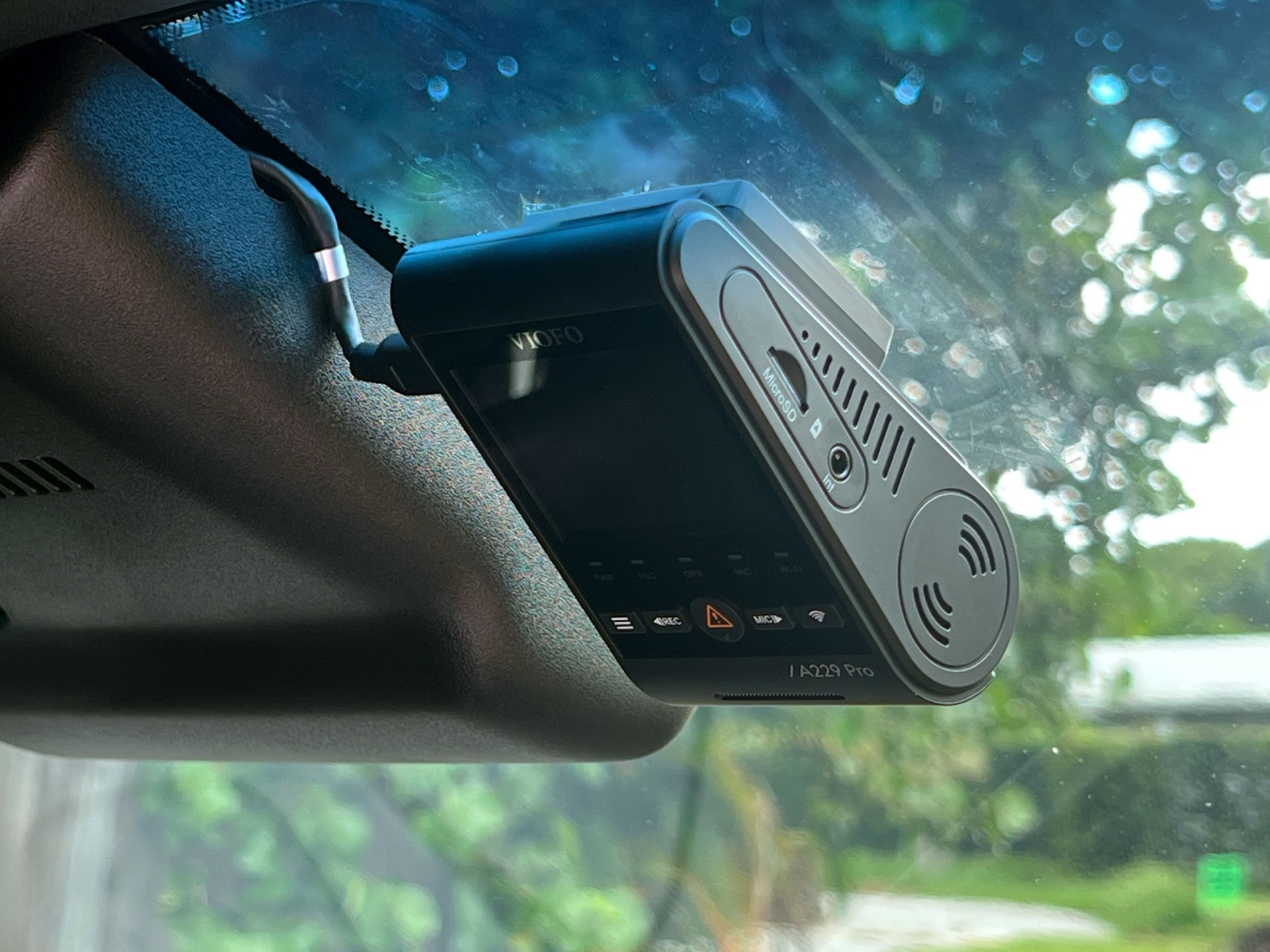 A dash camera professionally installed behind a rearview mirror, nearly invisible from the driver's seat